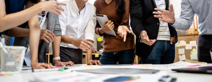 Group of coworkers standing around a table discussing a project