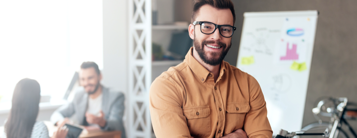 Happy bearded businessman leaning against a conference table