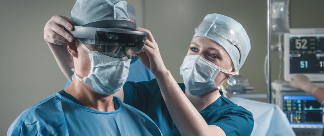 Nurse placing augmented reality glasses on a surgeon before performing remote surgery