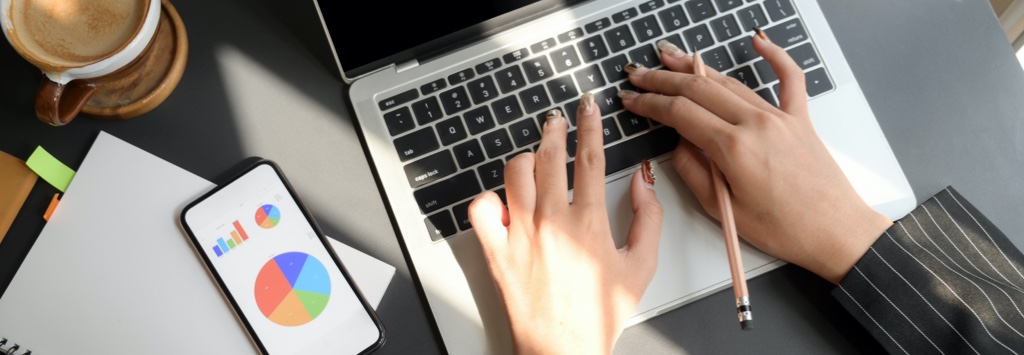 Businesswoman analyzing conversion report and typing on laptop