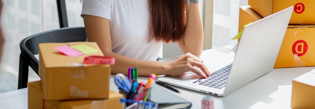 Woman sitting at desk using laptop while talking on the phone