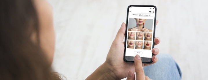 Young woman using augmented reality to try on different lip stick shades