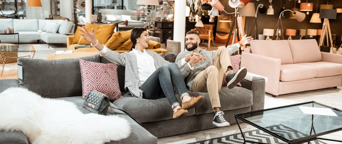 Happy Young Couple Sitting on Their New Couch in Showroom