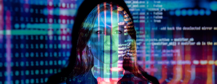 Women standing in front of a screen with code projected onto it