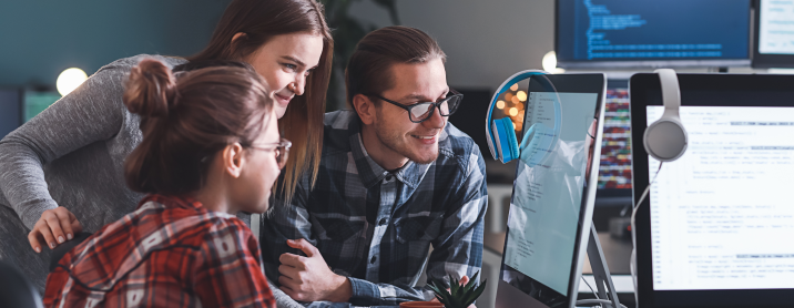 Group of coworkers happily discussing a project at their desks