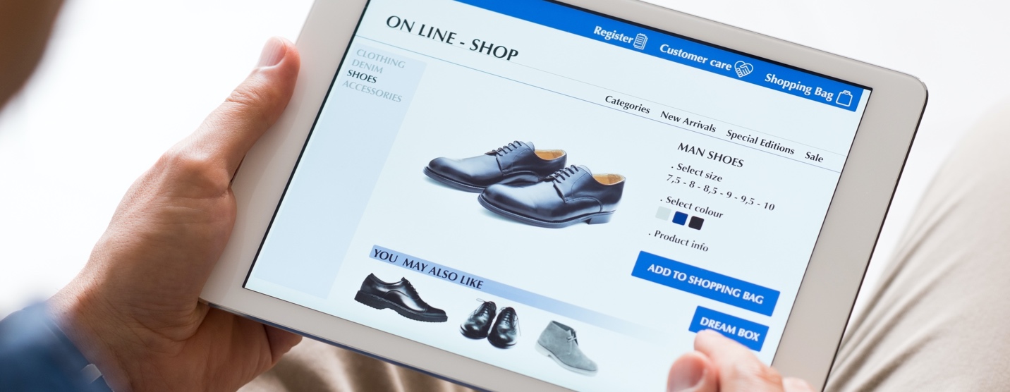 Man holding an iPad and looking at an eCommerce website selling shoes