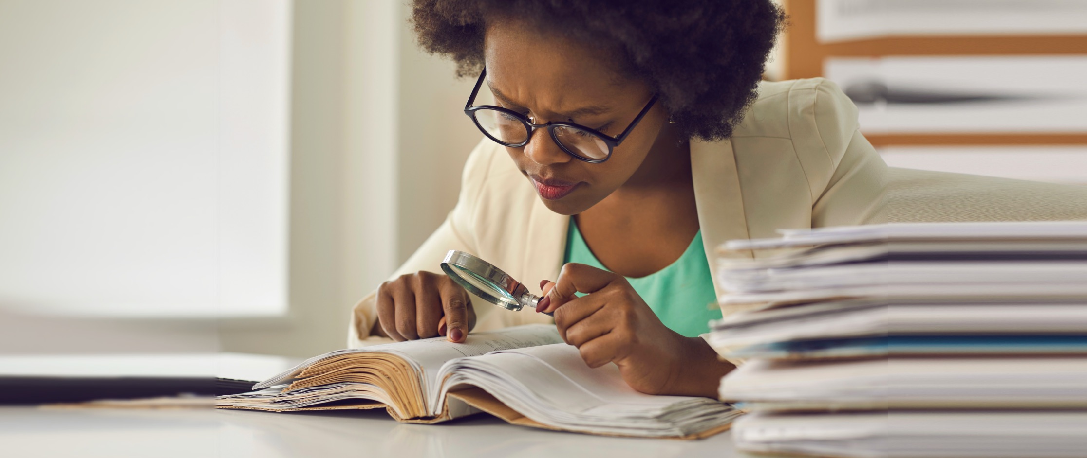 Woman reading dictionary with magnifying glass