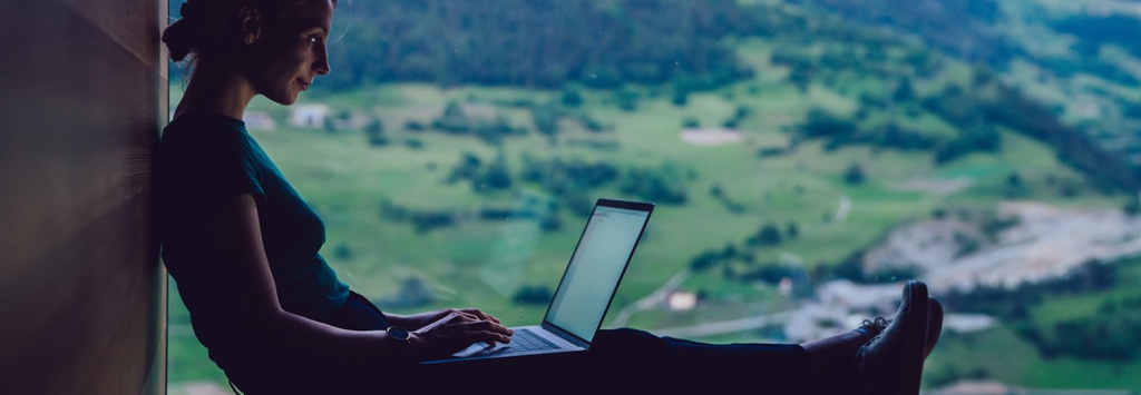 Young woman working remotely on vacation in the mountains