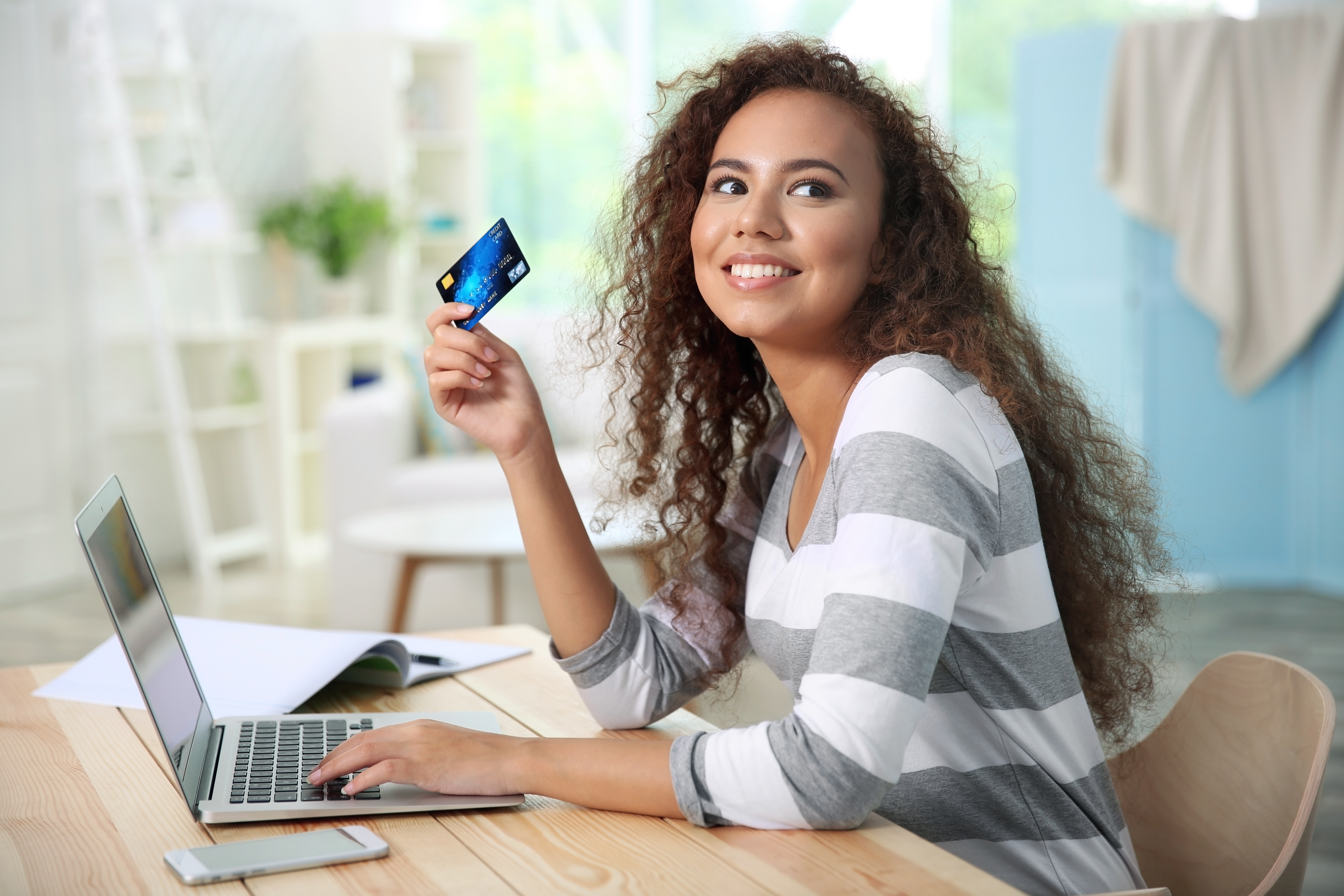 Woman at a laptop with her credit card purchasing items online