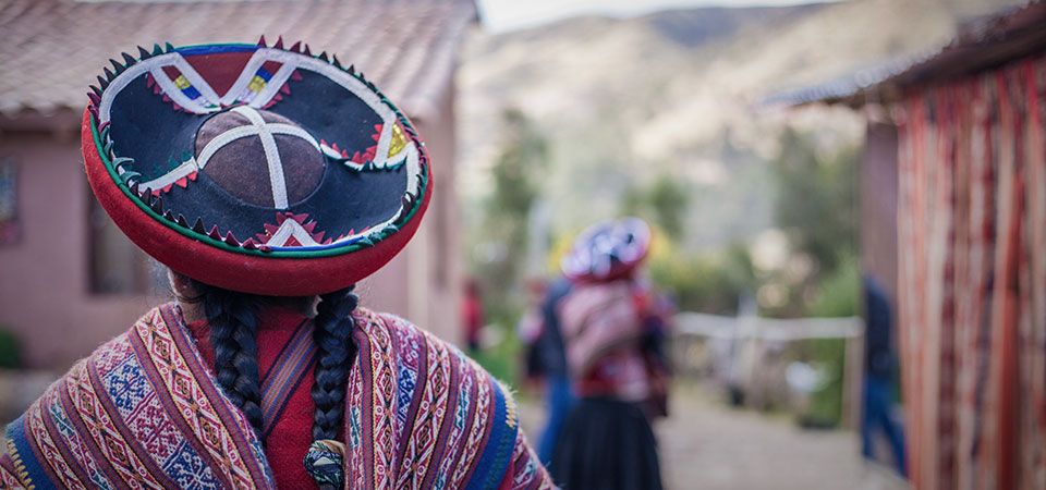 Andean women with braids and traditional hat and attire walking through the village of Chinchero of the Sacred Valley