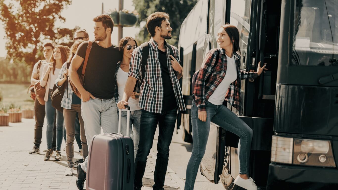 Passengers falling in line to ride in a black charter bus