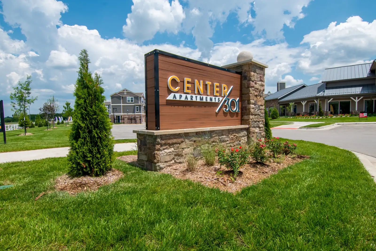 Outdoor monument sign for Center Apartments with a stone base and landscaped lawn.