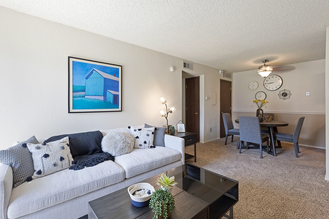 Living room in a modern apartment with a white sofa and dining area.