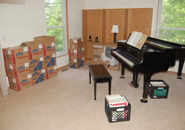 Boxes, bookshelf, and piano staging in the living room