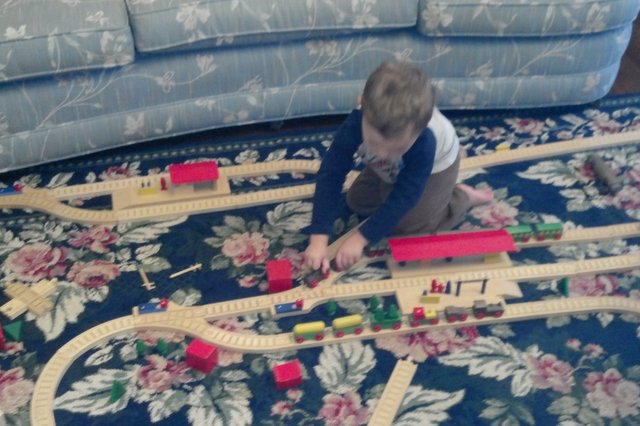 Calvin plays with a wooden train set at Nana's house