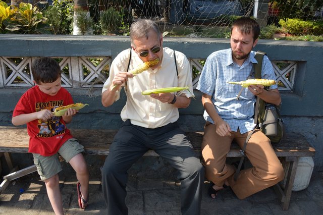 Willy, Grandpa, and Uncle Willy eat roasted corn on Elephanta Island