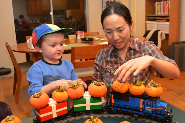 Julian watches Echo stack persimmons on the Lego train