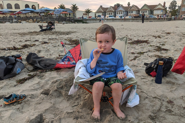 Julian eats pizza on the beach in Capitola