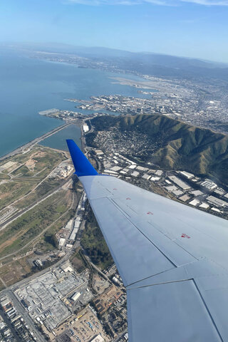 N956SW wing banks over San Bruno Mountain climbing out of SFO