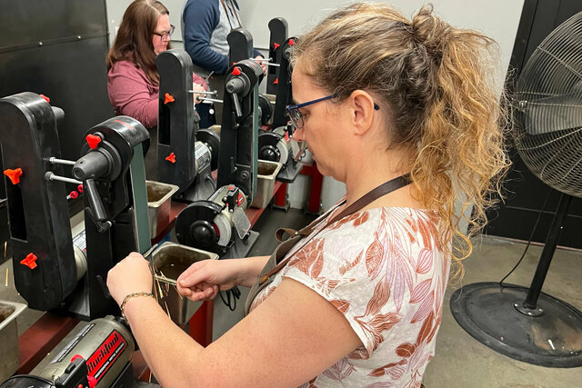 Kiesa sharpens a blacksmithed knife