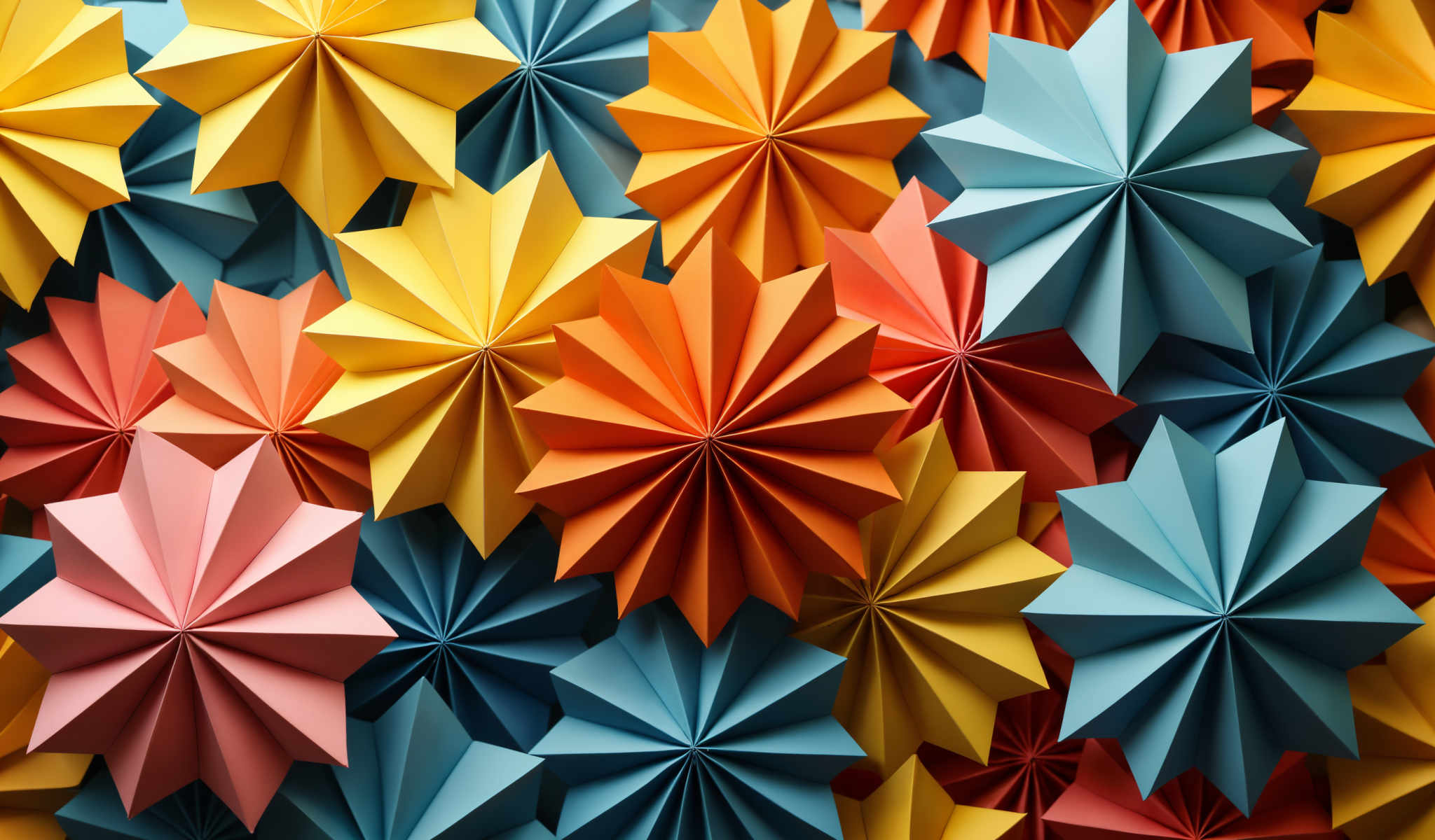 A collection of colorful origami stars are scattered across the image creating a vibrant and lively scene. The stars are made from paper and come in a variety of colors including yellow orange blue and red. They are arranged in a seemingly random pattern with some stars overlapping each other and others placed at different angles. The background of the stars is a solid blue color which contrasts with the bright colors of the origami. The image does not contain any text or other discernible objects. The overall impression is one of a playful and creative display of origami art.