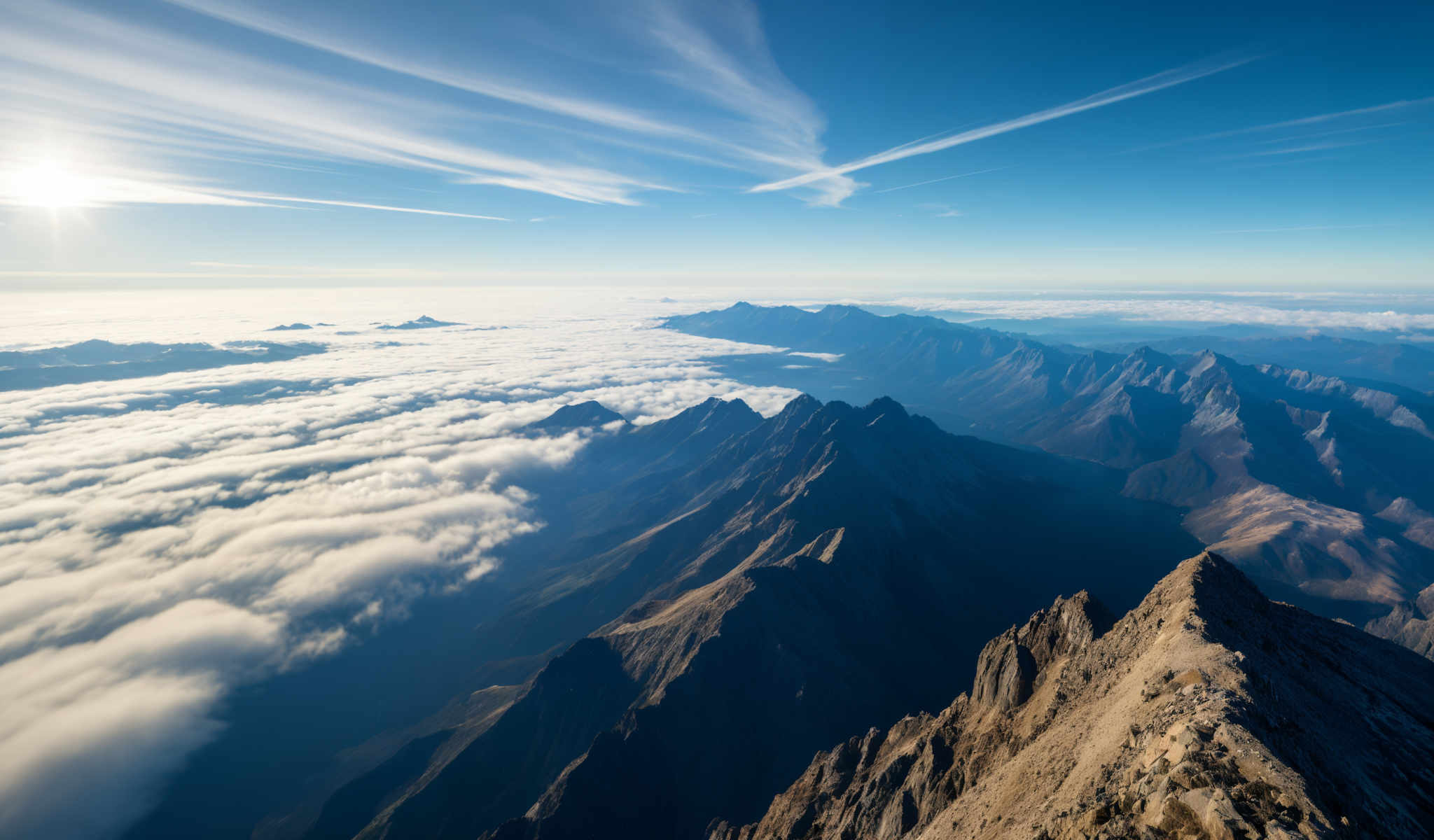 A breathtaking view of a mountain range with a clear blue sky above. The mountains are covered in a blanket of snow and clouds creating a serene and beautiful landscape. The image captures the majesty of nature and the grandeur of the mountains. It's a stunning representation of the beauty of the natural world.