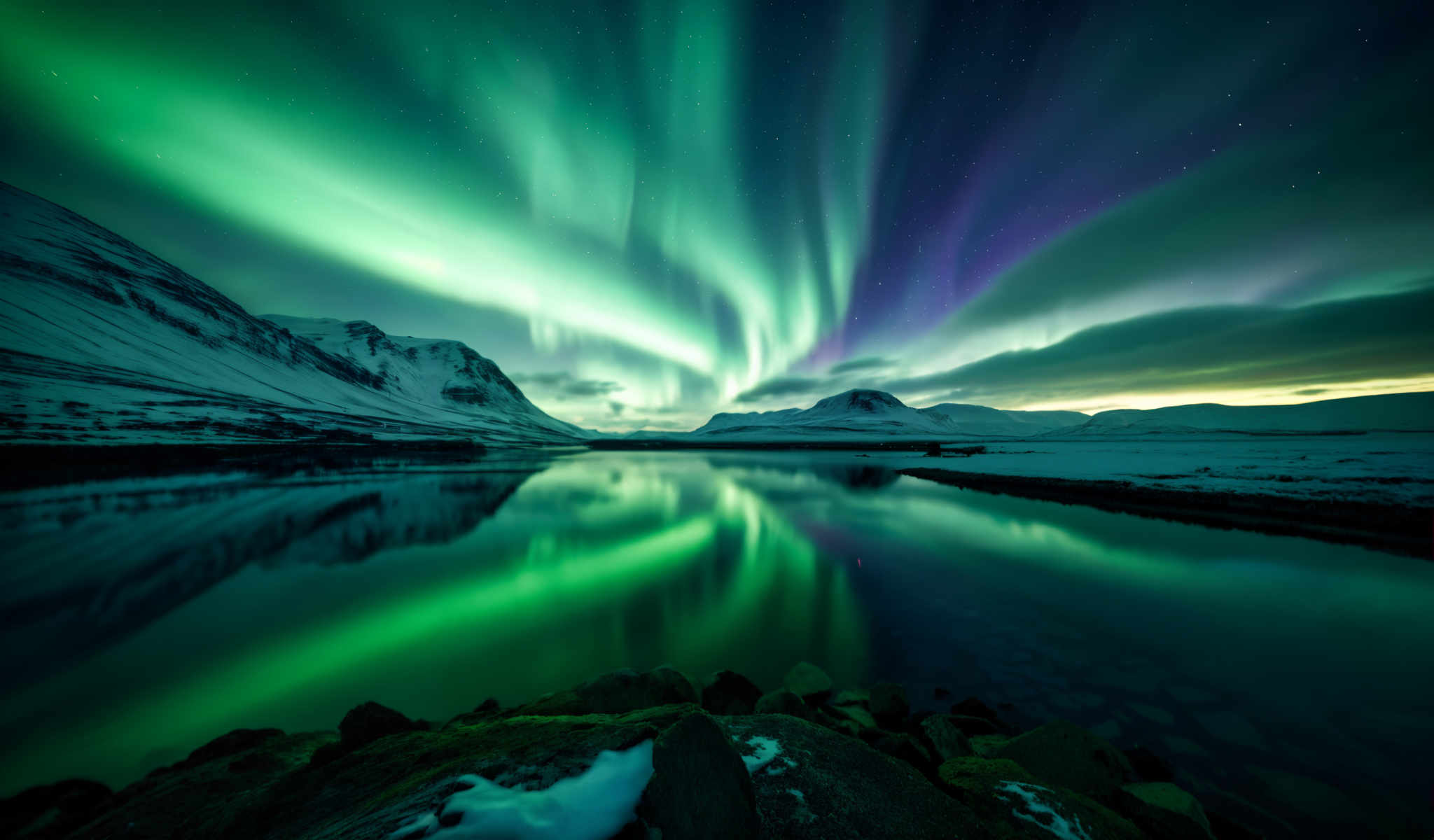 A serene scene of a lake with the Aurora Borealis in the background. The lake is surrounded by mountains and the sky is dark. The Aurora Boreal is a beautiful display of green and purple lights. The mountains are covered in snow and the lake is calm. The sky is clear and the stars are visible. The image is taken from a high vantage point looking down on the lake. The colors in the image are vibrant and the lighting is natural. The overall atmosphere of the photo is peaceful and serene.