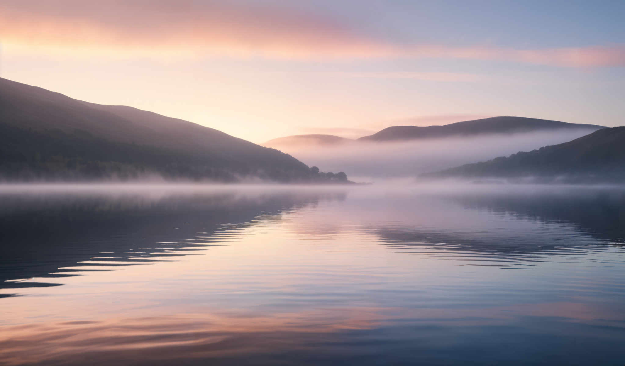 A serene lake with foggy mountains in the background.