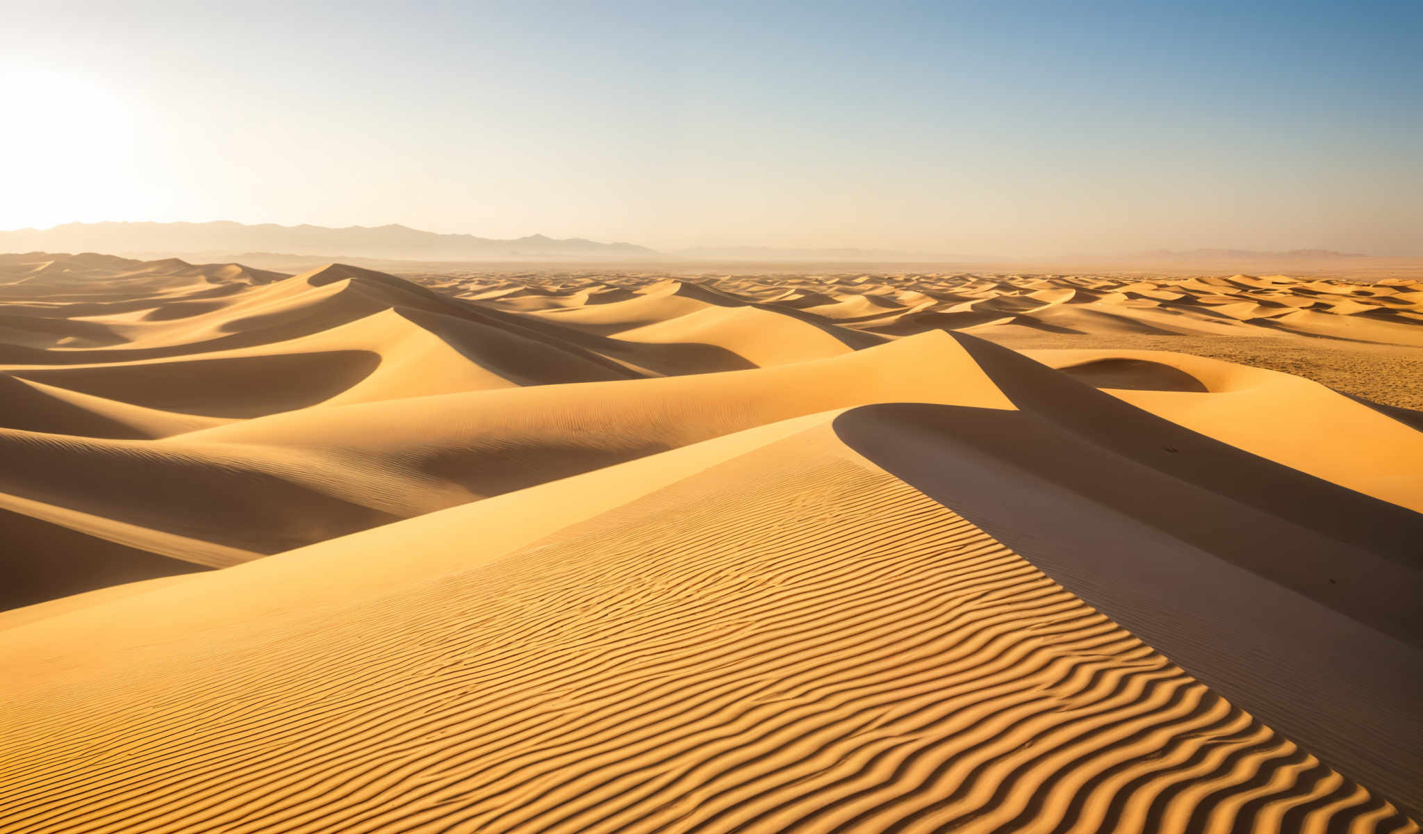 A desert landscape with sand dunes and mountains in the background.