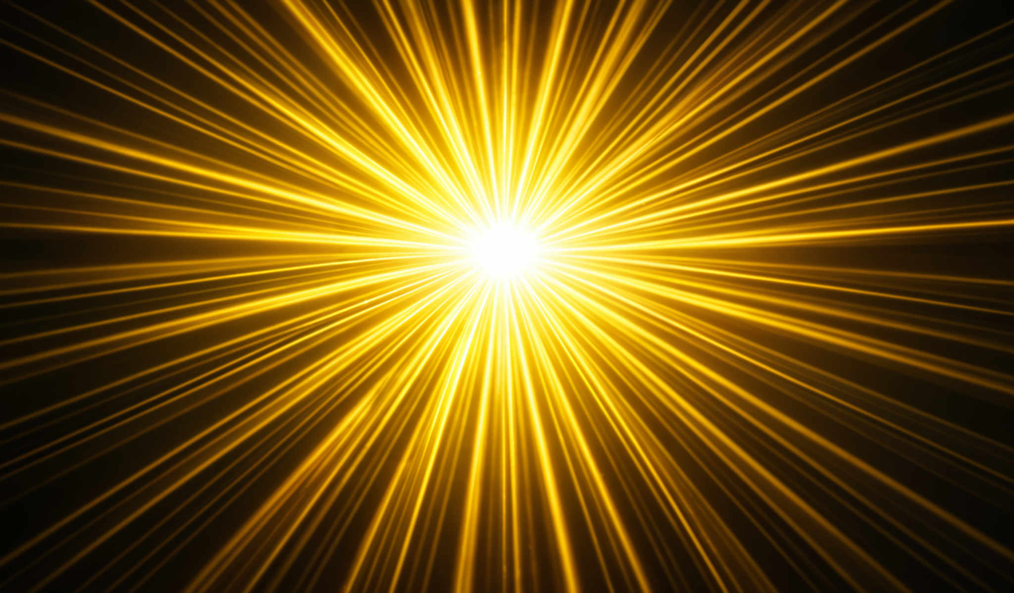 The image showcases a radiant burst of golden-yellow light emanating from a central point. The light rays radiate outwards in all directions, creating an explosive effect. The background is dark, which accentuates the brightness and intensity of the light. The overall shape can be described as an explosion or a starburst, with the light ray lines converging towards the center and then dispersing outwards.