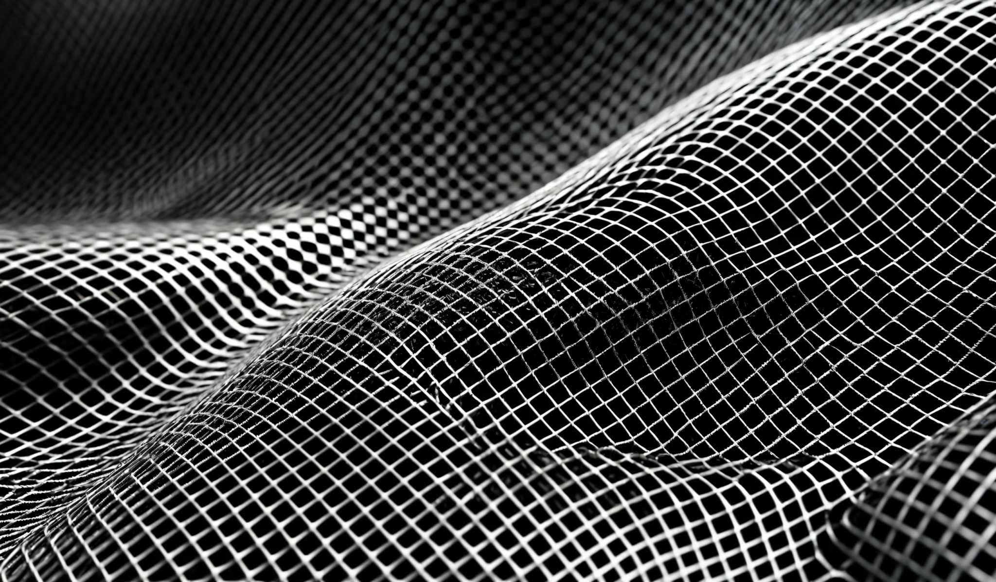 The image showcases a monochromatic, predominantly black and white, abstract representation. It features a three-dimensional mesh or net-like structure that appears to be wavy or undulating. The mesh is intricately detailed, with fine lines and intersections, creating a sense of depth and movement. The play of light and shadow accentuates the curves and folds of the mesh, giving it a dynamic and fluid appearance.