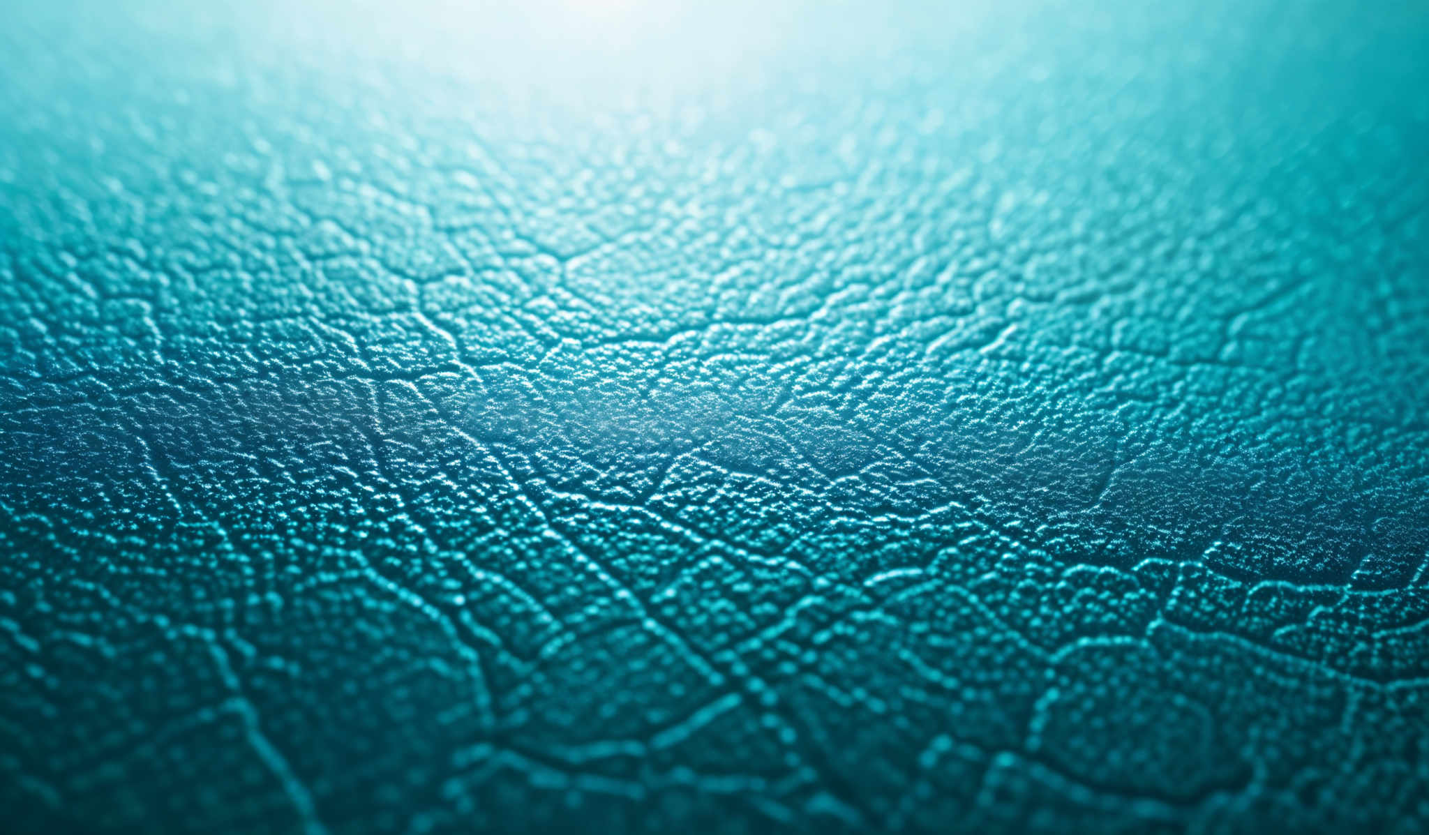 The image showcases a close-up view of a textured surface. The dominant color is a shade of turquoise or teal. The texture appears to be cracked or cracked in a pattern reminiscent of dried mud or parched earth. The surface has a rough and uneven appearance, with the cracks forming intricate, interconnected patterns. The lighting in the image accentuates the depth and intricacy of the texture, giving it a three-dimensional feel.