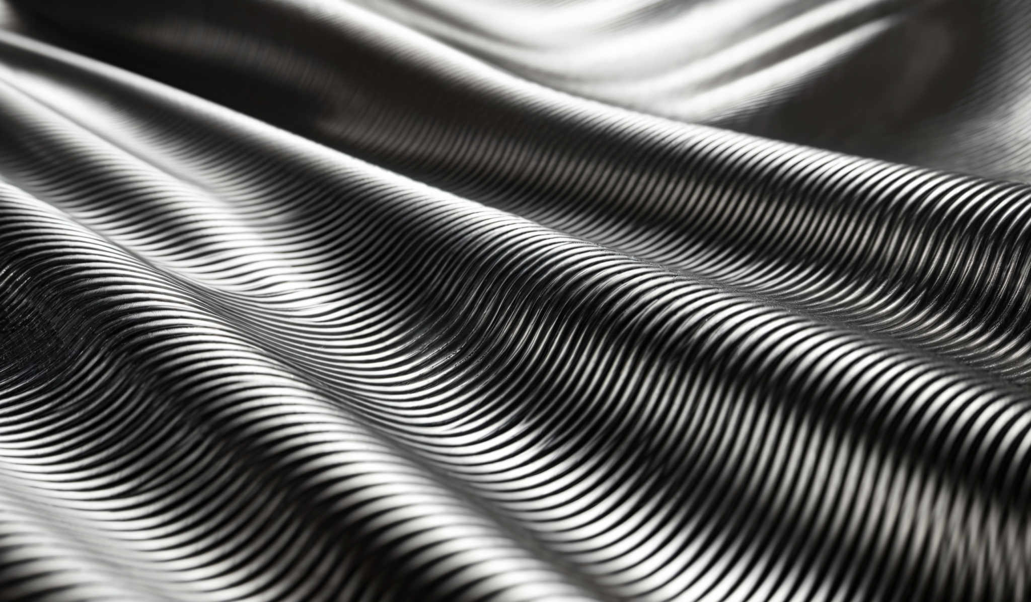 The image showcases a close-up of a textured surface with a plethora of parallel lines. The colors are predominantly shades of gray, with a metallic sheen. The shape is wavy, resembling a series of undulating ridges or waves. The lines are uniformly spaced, creating a rhythmic pattern that draws the viewer's eye inward.