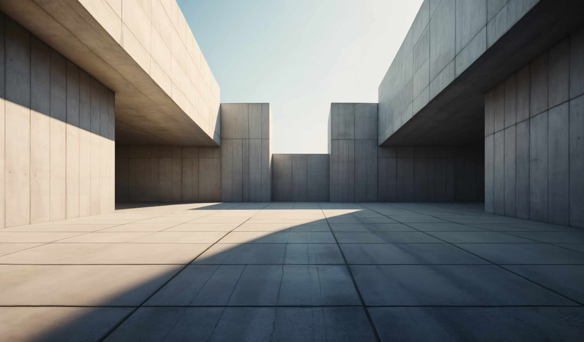 A large concrete structure with a flat roof and a flat floor. The structure is divided into three sections with the middle section being the largest. The building is made of concrete and has a flat rectangular shape. The roof and floor are also made of the same material. The sky is visible in the background and the building is located in an open area. The image does not contain any text or other objects. The relative positions of the sections of the building are such that the middle one is in the center with two smaller sections on either side. The sun is shining on the building casting shadows on the floor.