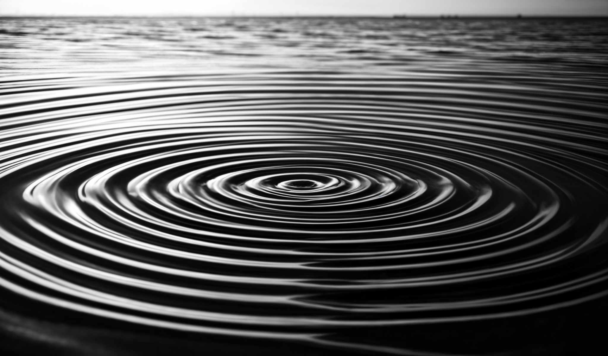 A black and white image of a water surface with ripples.