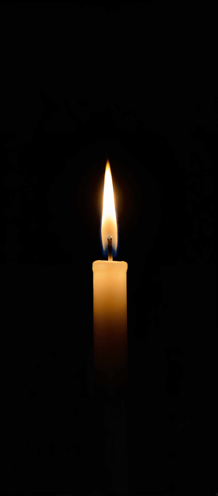 The image captures a single lit candle in a dark setting. The candle with its blue and white flame stands out against the black background. The flame dances and flickers casting a warm glow that illuminates the surrounding area. The wax of the candle is a soft pale yellow contrasting with the deep black of the background. This image evokes a sense of solitude and tranquility as the candle's flame is the only source of light in the otherwise dark environment. The art style of the image is simple yet powerful with the candle and its flame being the sole focus. The subject of the photo is the candle and the motif is the play of light and shadow color and contrast. The image does not contain any text or other objects and there are no actions taking place. The relative position of the objects is straightforward - the candle in the center the flame rising from it and all of it set against the dark background.