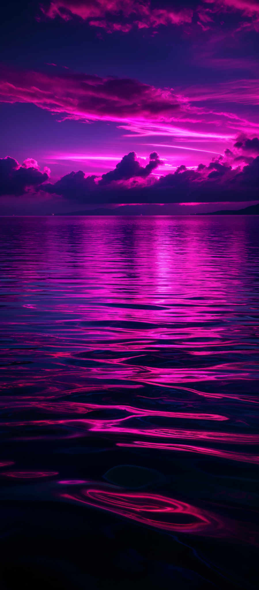 The image showcases a vibrant and dramatic sunset over a body of water. The sky is painted with hues of deep purple, magenta, and pink, interspersed with darker clouds. The sun, though not directly visible, casts a radiant glow, reflecting its colors onto the water below. The water's surface is rippled, capturing the sunset's vibrations in shades of pink and purple. The horizon line is faintly visible, separating the sky from the water.