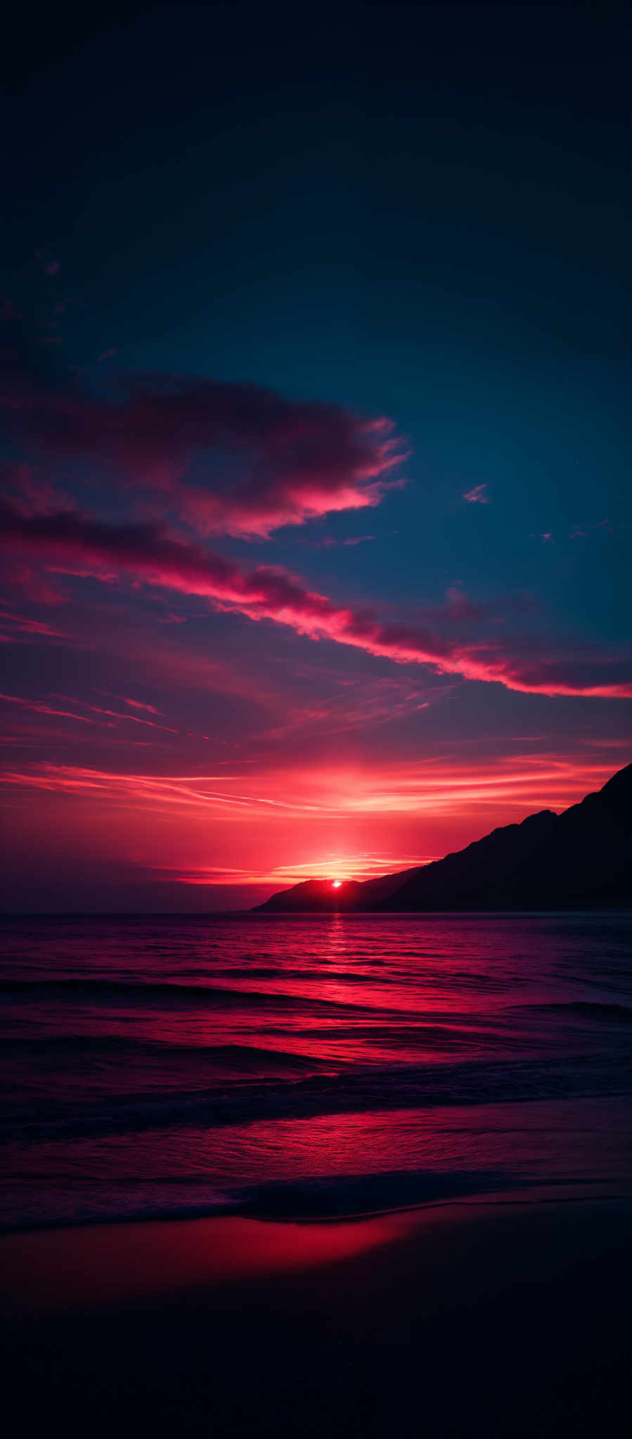 The image showcases a breathtaking sunset over a beach. The sky is painted with hues of deep blue, transitioning to vibrant shades of pink and orange near the horizon. Wispy clouds are scattered across the sky, reflecting the colors of the sunset. The sun itself is just below the horizon, casting a golden glow over the calm waters of the beach. Waves gently lap the shore, reflective of the fiery sky above. In the distance, a silhouette of a mountain or hill can be seen.