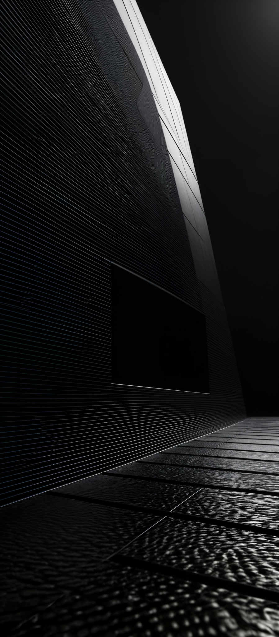 The image predominantly features shades of black, white, and gray. The primary shape is a large, angular structure with a smooth, ribbed texture. The structure has a rectangular opening, and its surface reflects light, creating a contrast between light and shadow. The ground appears to be made of a textured material, possibly tiles, with a pattern that mirrors the structure above.