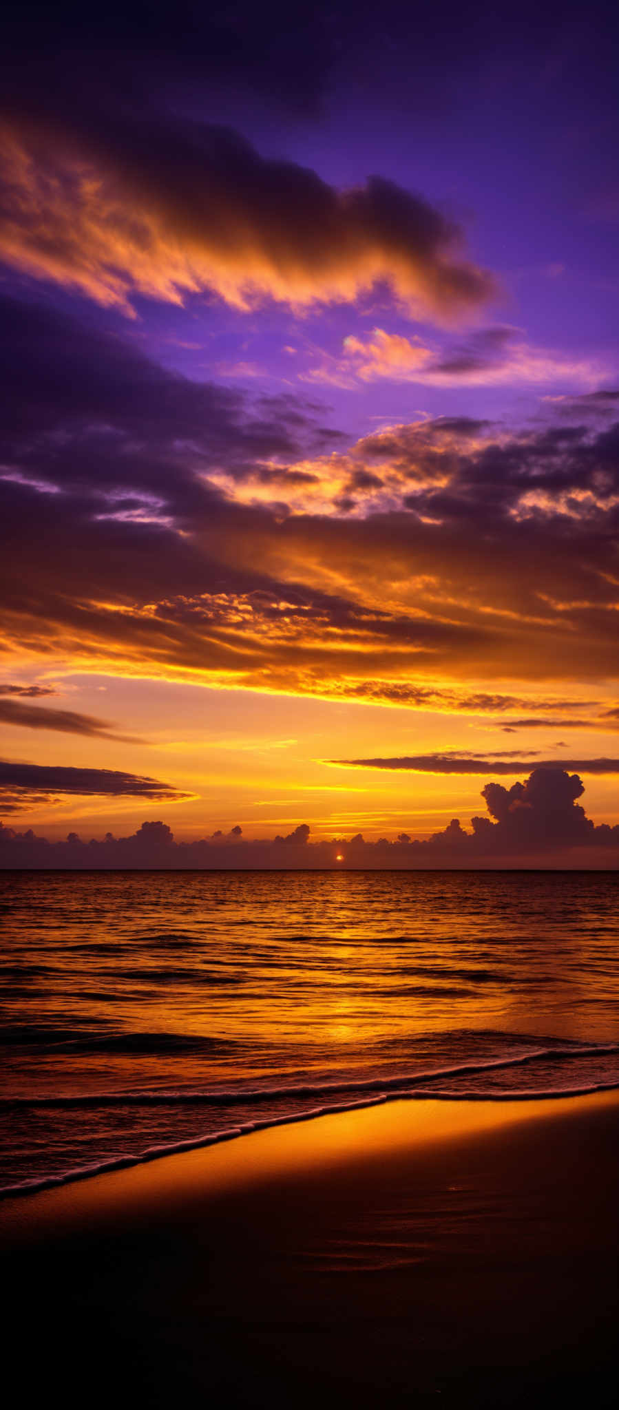 The image showcases a breathtaking sunset over a beach. The sky is painted with a myriad of colors, ranging from deep purples and blues at the top to fiery oranges and yellows near the horizon. The clouds are scattered across the sky, reflecting the colors of the sunset. The sun itself is visible near the center, casting a golden hue over the water. The water reflects the colors from the sky and the sun, creating a shimmering pathway that leads to the beach. On the beach, the dark silhouette of the land is contrasted against the bright reflection of the sky.