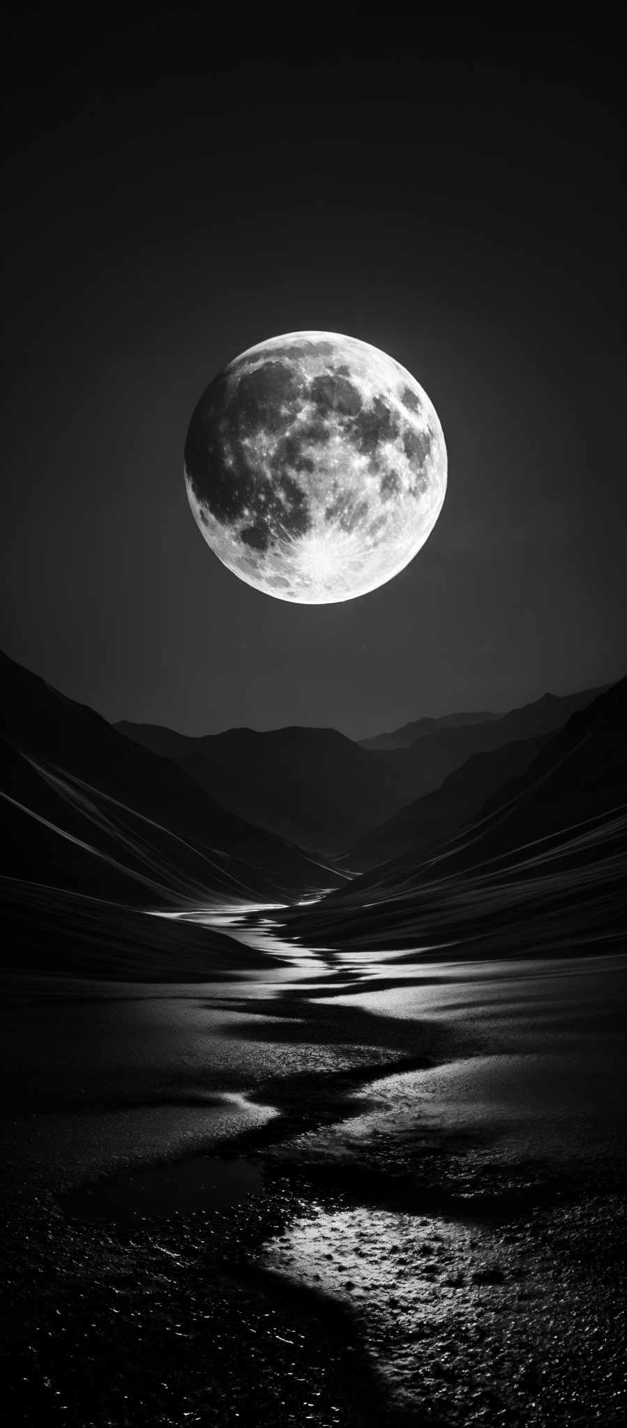 The image predominantly features monochromatic shades of black, white, and gray. The moon is a bright, round celestial body with a textured surface, showcasing craters and surface irregularities. It is set against a dark, starry sky. Below the moon, there's a serene landscape of undulating hills or mountains, with their contours beautifully highlighted. The terrain appears to be covered with a reflective surface, possibly water or wet sand, which reflects the moon's light, creating a shimmering pathway that snakes through the landscape.