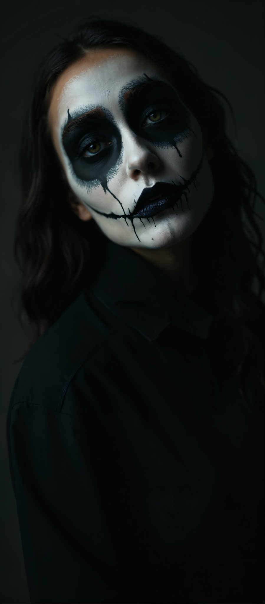 A woman with black face paint and long dark hair.