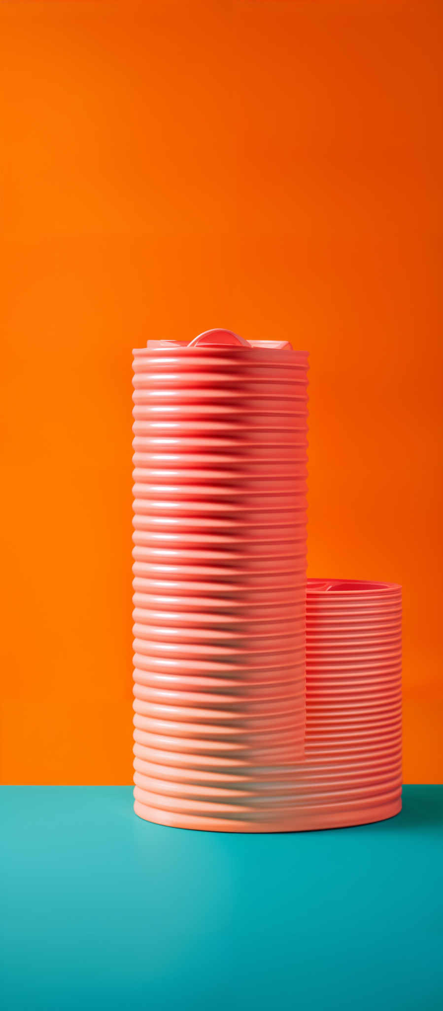 The image showcases a cylindrical object with a ribbed texture, stacked on top of each other. The object is placed against a vibrant orange background. The bottom of the image reveals a teal surface. The color palette is vivid, with the orange providing a warm backdrop and the teal offering a cool contrast.