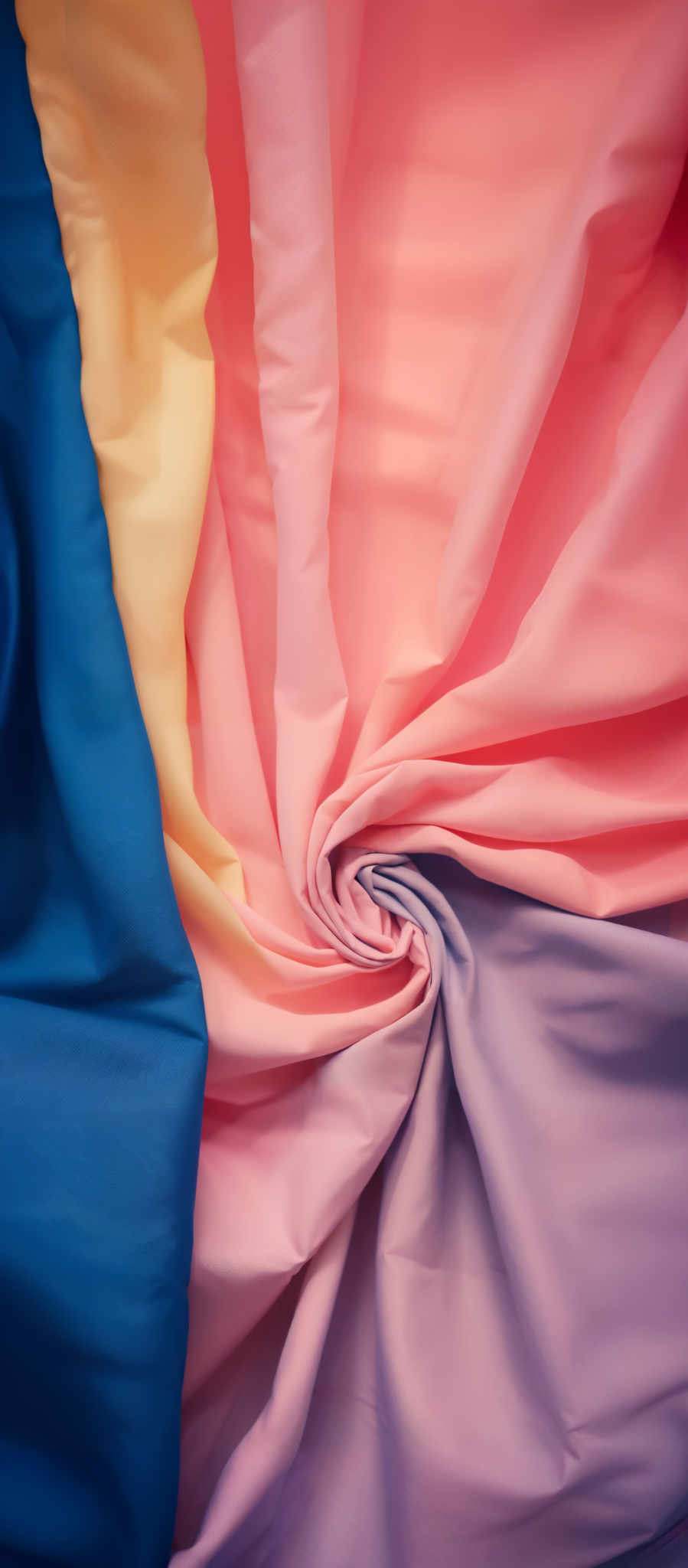 The image showcases a vibrant and colorful fabric with multiple layers. The dominant colors are shades of pink, purple, and blue. The fabric appears to be smooth and has a sheen to it. The layers are folded in a way that creates a swirling effect, with the colors blending seamlessly into one another. The overall impression is one of softness, elegance, and a play of warm and cool tones.