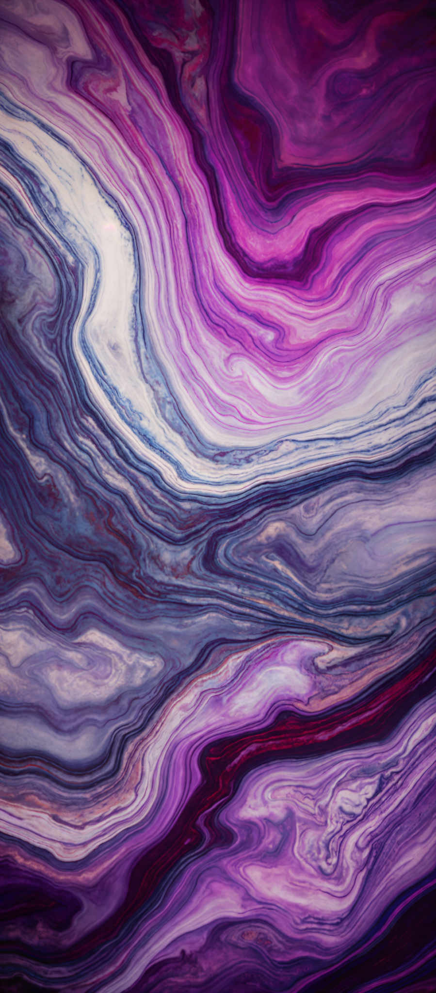 The image showcases a vibrant and intricate marbled pattern. It features a mix of deep purples, blues, and whites, creating a swirling effect. The shapes are fluid and organic, resembling waves or flowing water. The patterns are layered, with some areas having a more dense and opaque appearance while others are lighter and more translucent.