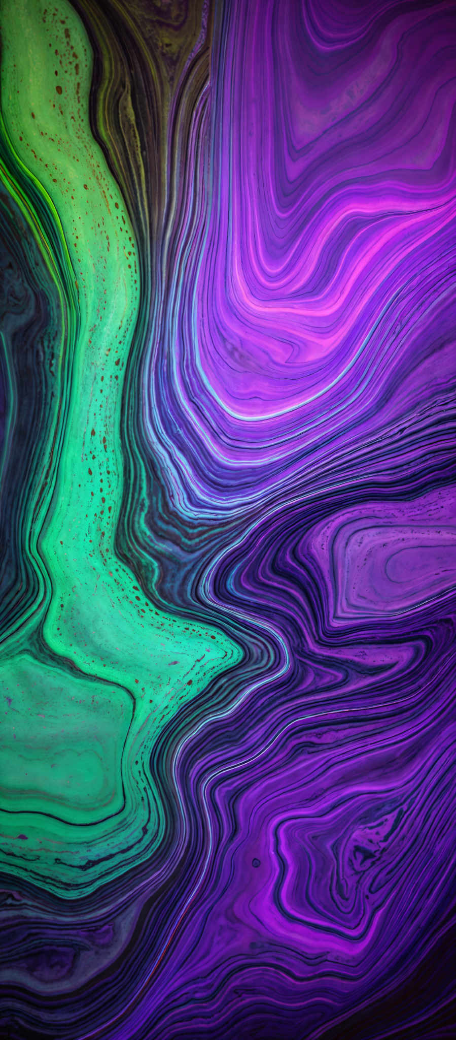 The image showcases a vibrant and intricate pattern of swirling colors. The dominant colors are shades of green, purple, and a hint of blue. The swirls are fluid and wavy, resembling the flow of water or the texture of marble. There are also speckles of a golden-yellow hue scattered throughout, adding a touch of contrast to the predominantly cool color palette.