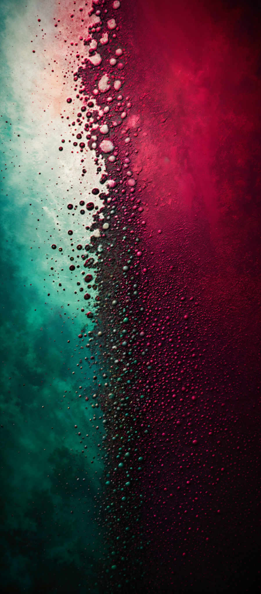 The image showcases a gradient of colors transitioning from a deep teal at the top to a rich red at the bottom. The top portion is dominated by a serene teal, which gradually fades into a more intense shade of blue-green. As we move downwards, the color transitions into a deep red, interspersed with numerous small droplets that appear to be condensing or frozen. The droplet formation gives the image a crystalline or icy appearance, suggesting a cold or frosty environment.