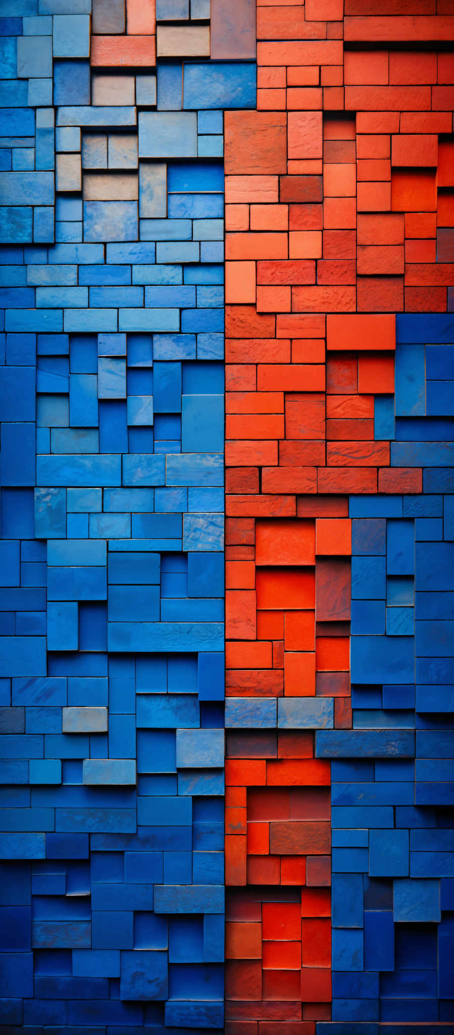 The image showcases a wall made up of rectangular blocks arranged in a mosaic pattern. The blocks are of varying sizes and are painted in two distinct colors: blue and orange. The blue blocks are arranged in an alternating pattern with the orange blocks, creating a visually appealing contrast. The texture of the blocks appears to be slightly rough, and the play of light and shadow gives depth to the image, making the colors pop.