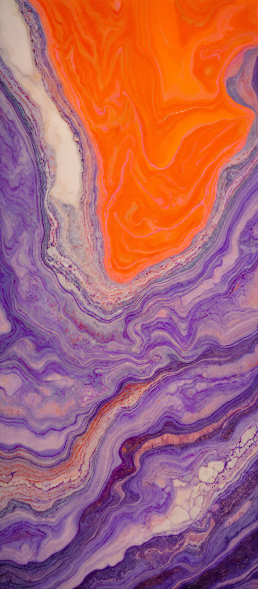 The image showcases a vibrant and intricate pattern of swirling colors. Dominant colors include shades of blue, purple, and a striking bright orange. The swirls create a marbled effect, reminiscent of agate or fluid art. The patterns are layered, with some areas having a more dense and concentrated flow of color, while others are more spread out. The overall impression is one of fluidity, movement, and natural beauty.