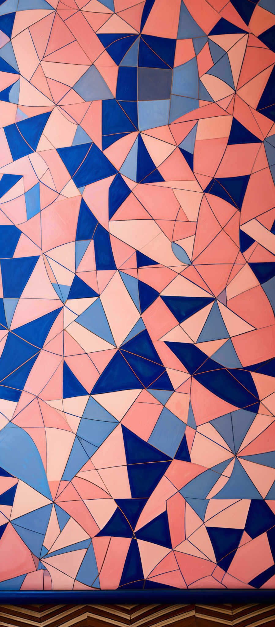 The image showcases a geometric pattern composed of interlocking triangles. The triangles come in various shades of pink, blue, and white. The pattern is intricate, with overlapping and intersecting triangular edges, creating a mosaic-like appearance. The bottom of the image displays a section of a wall with a distinctive zigzag pattern in a dark color, possibly a type of molding or decorative trim.